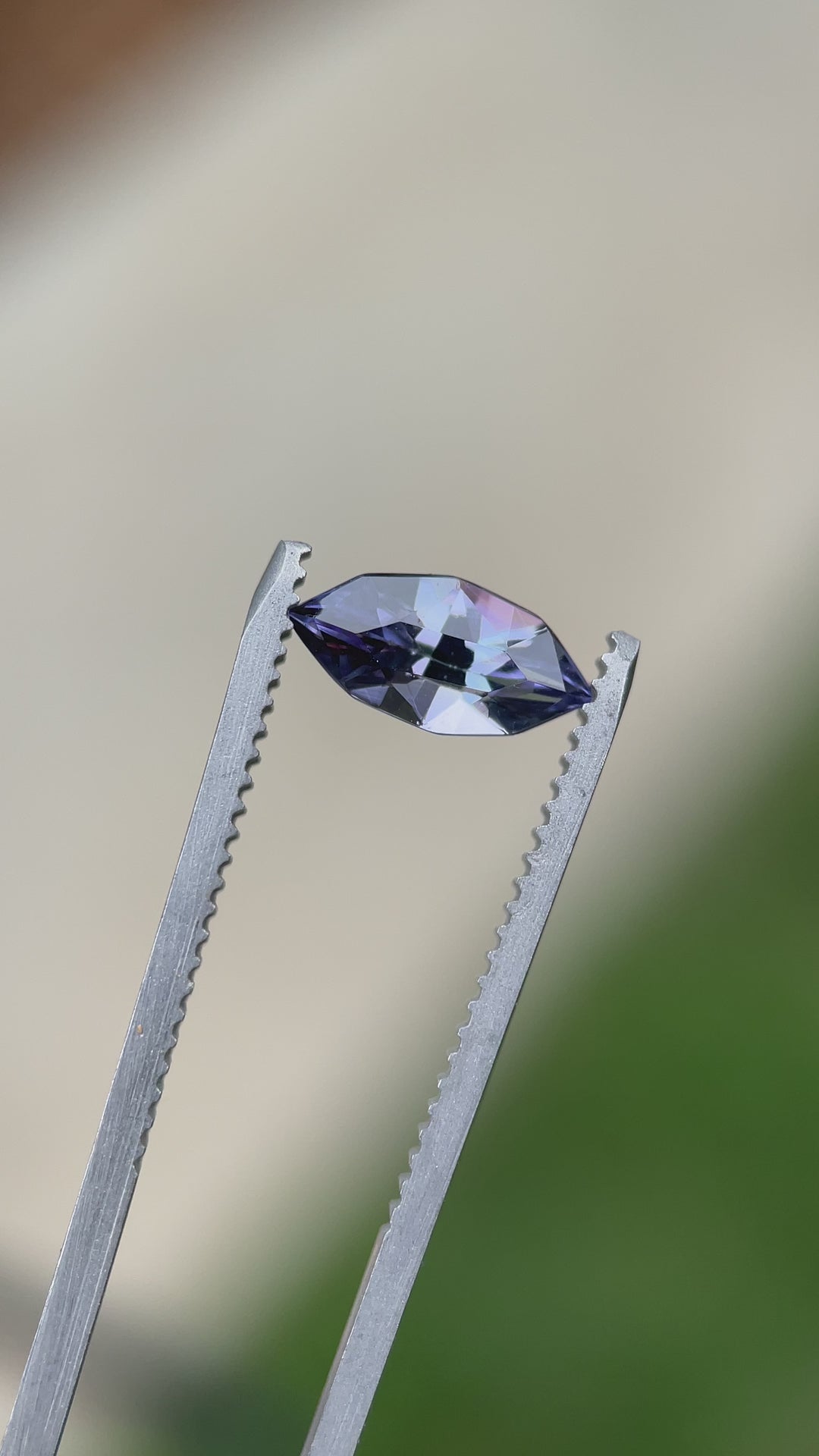 Close-up video of a custom geometric marquise Tanzanite in tweezers, capturing its vibrant purple flash and precision faceting.