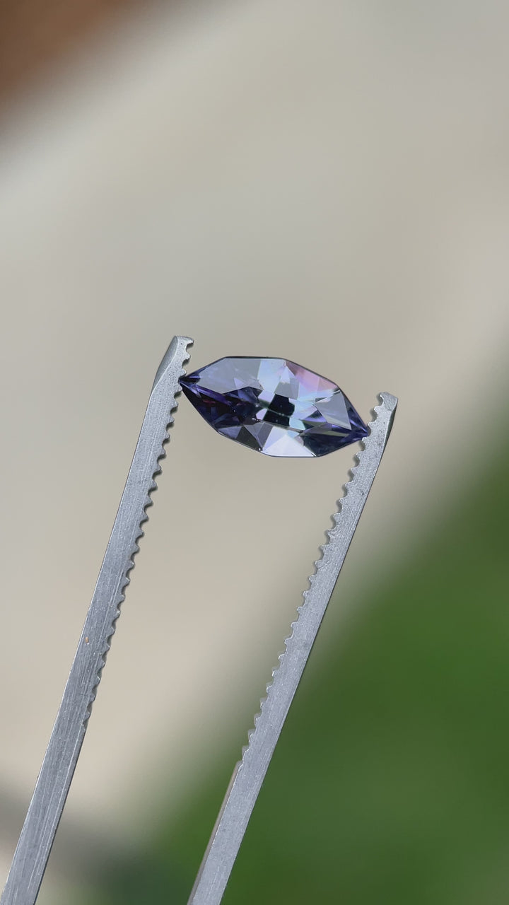 Close-up video of a custom geometric marquise Tanzanite in tweezers, capturing its vibrant purple flash and precision faceting.
