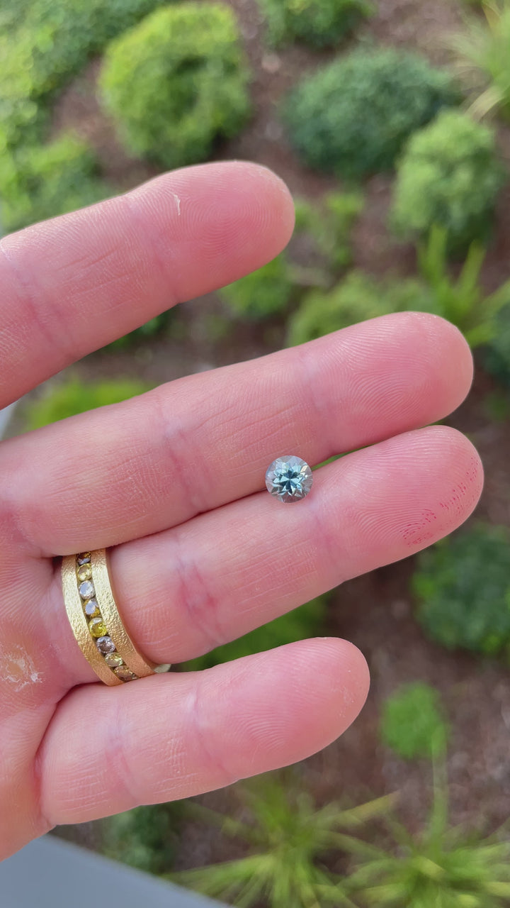Video of a 2.04ct round brilliant sapphire revealing its shifting seafoam, green, and teal hues under changing lighting angles.