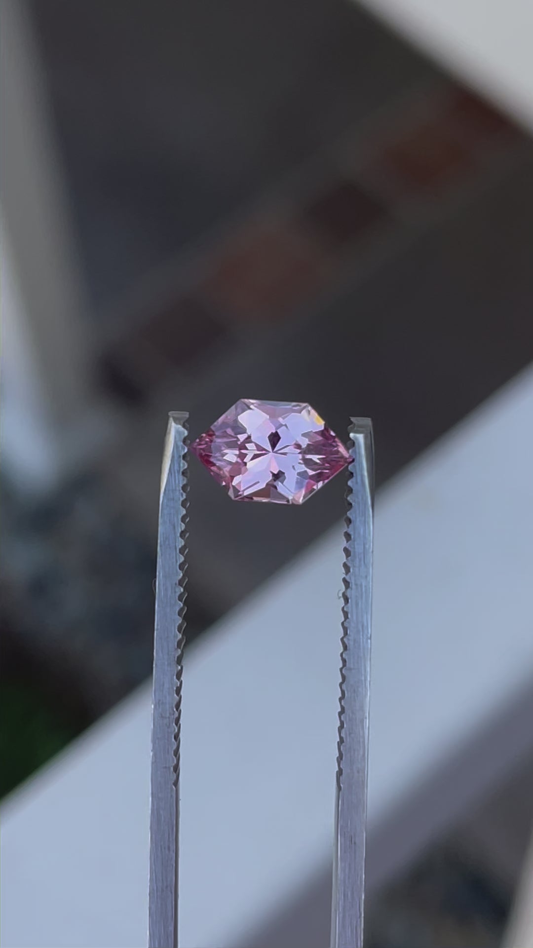 Detailed footage of a 1.61 carat blush pink and peach sapphire, focusing on the modified brilliant hexagon cut. The video showcases the gemstone's peachy-pink hues and exceptional clarity from different angles.