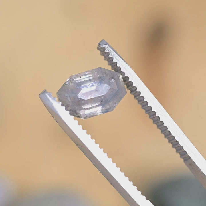 Loose 2.40 carat heated gray purple sapphire from Montana turning in natural light, revealing shifts between soft gray and violet tones.