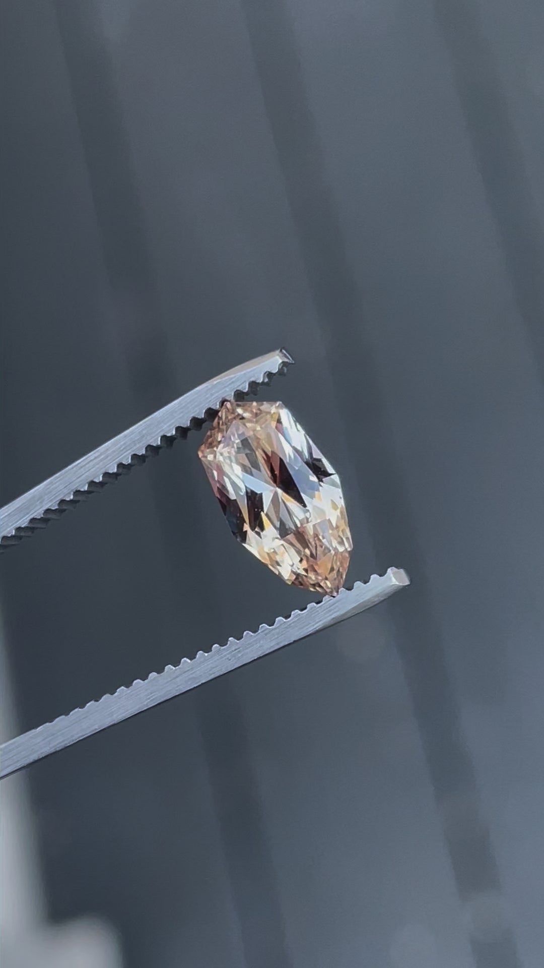 A rotating 2.07-carat peach and champagne sapphire with a custom geometric shield brilliant cut. The video highlights the gemstone's vibrant tones and intricate facets as it moves. The sapphire, untreated, measures 11.02mm by 5.87mm by 3.94mm and comes from Sri Lanka.
