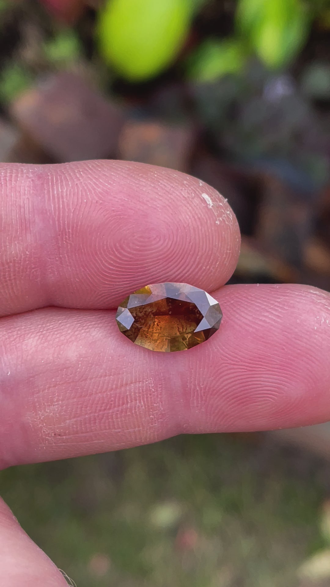 A captivating video of a 3.45-carat sapphire displaying its unique color shifts from earthy tones to a radiant golden pumpkin. The oval gemstone sparkles as it moves under changing lighting conditions.