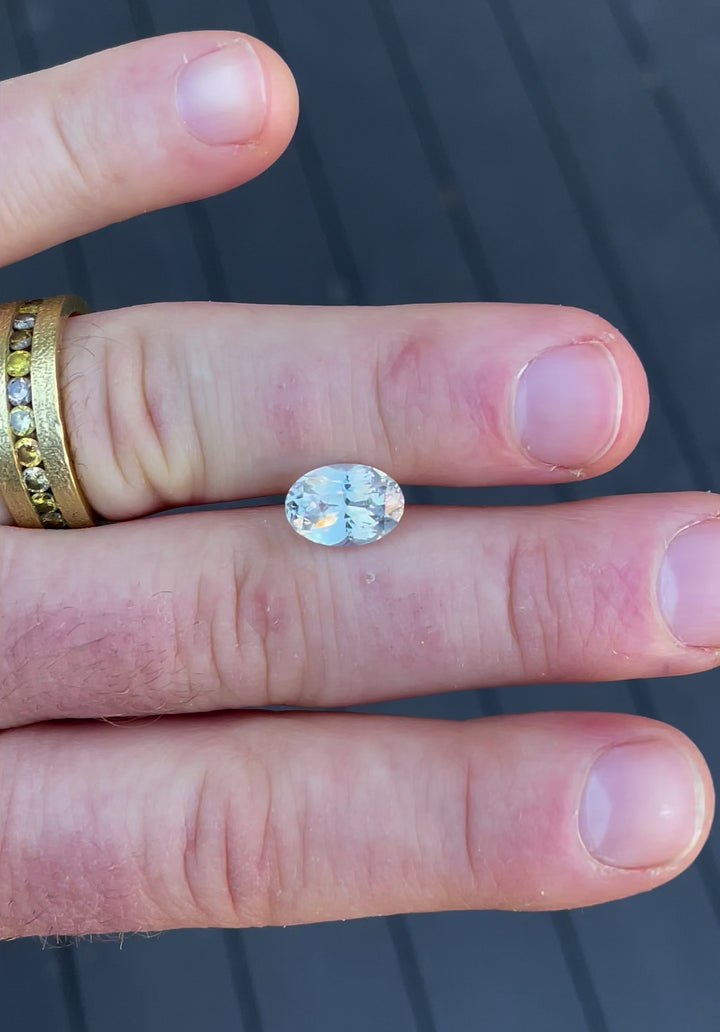 A mesmerizing video of a 4.23-carat opalescent white sapphire, highlighting its oval cut and reflective opalescent hues in different angles.