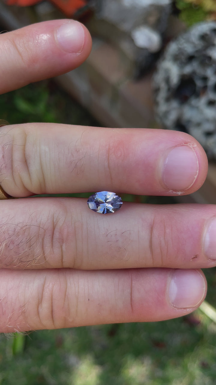 Interactive video presentation of a Tanzanite gemstone weighing 1.79 carats, displaying a custom geometric oval shape with shades of gray, lavender, and purple. The video captures the natural beauty and the precise facets of this high-quality gem from Merelani Hills, Tanzania.