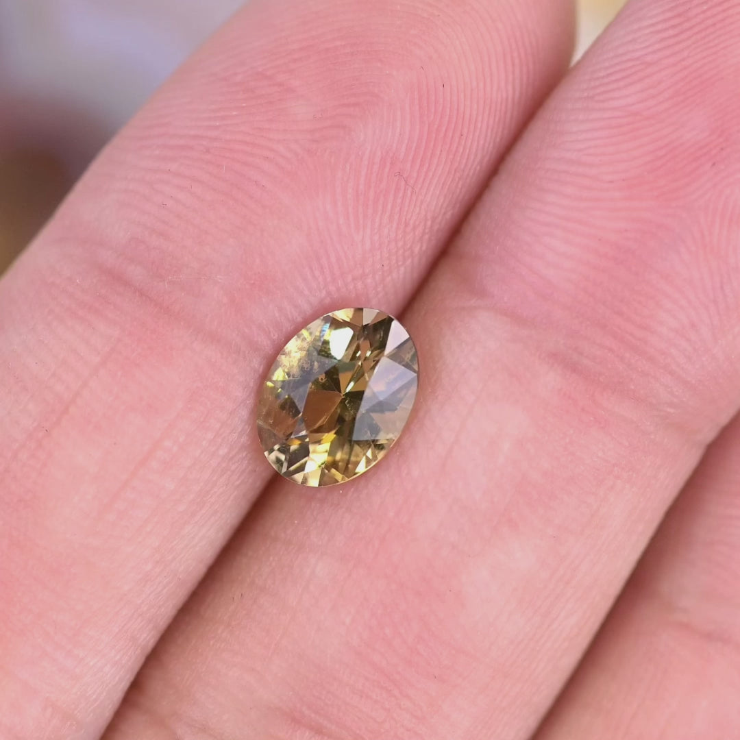 Hand-rotated 1.68CT green yellow Tanzanite oval, video showing color shift, sparkle, and custom mixed cut facet performance