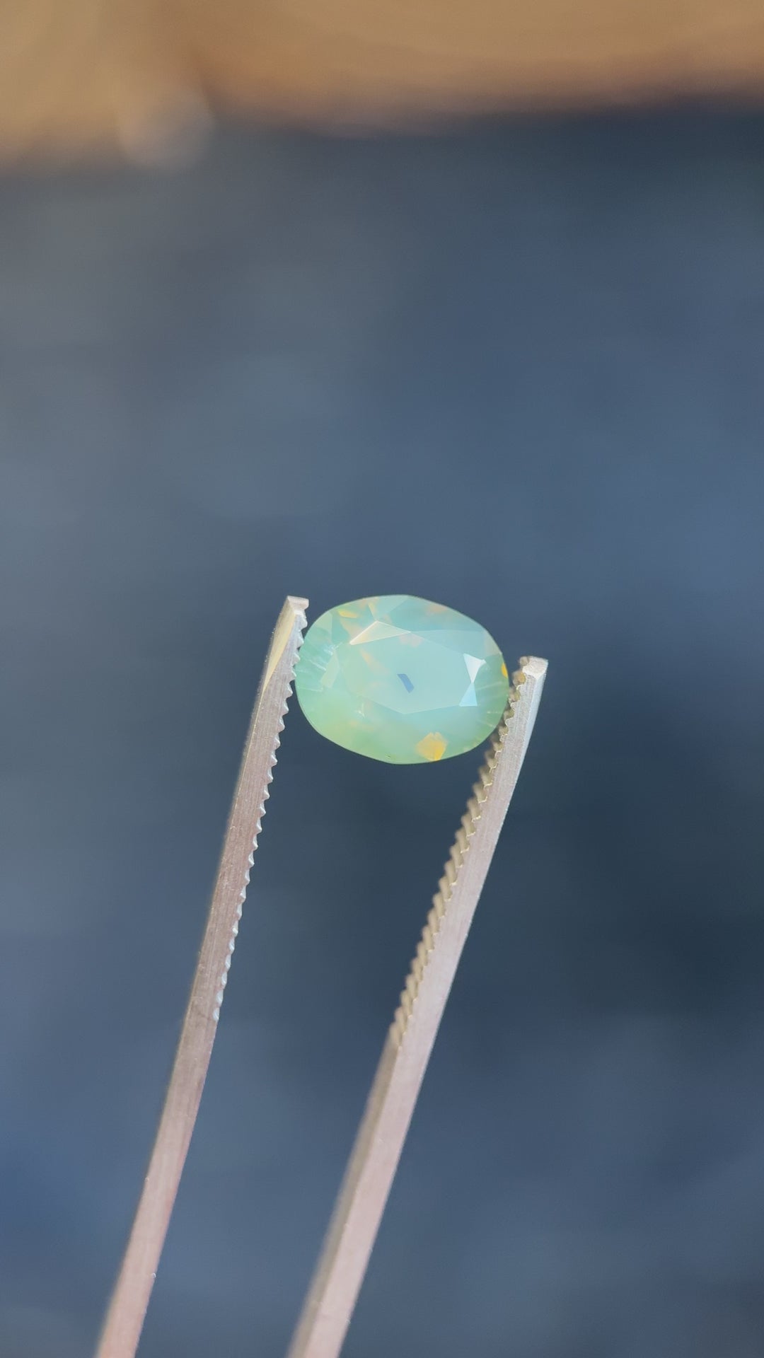 Rotating view of an untreated 4.19-carat sapphire on vibrant yellow moss, revealing its deep teal tones and sparkling mixed brilliant cut.

