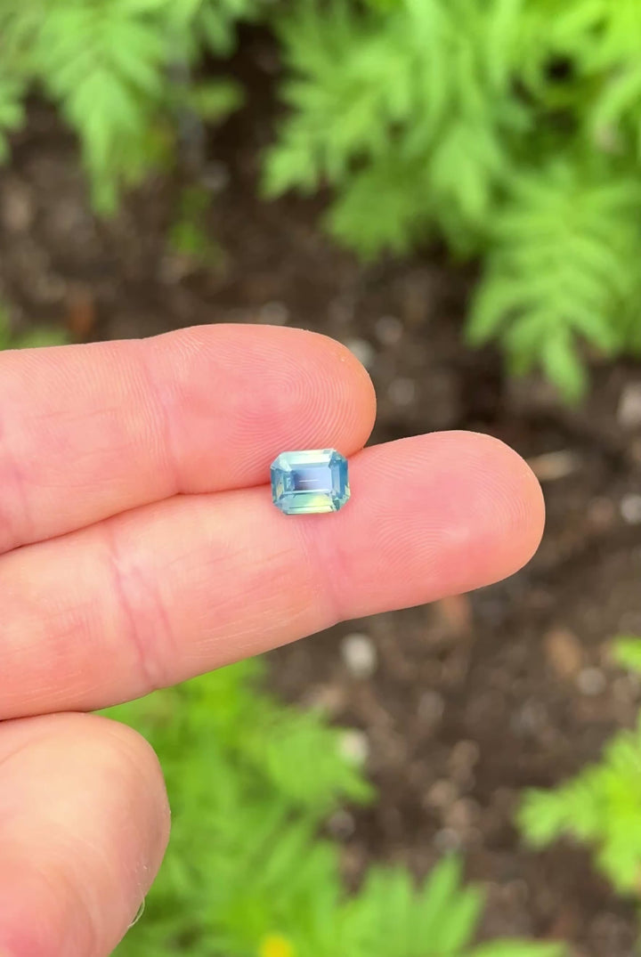 2.58ct opalescent yellow teal blue green sapphire rotating in hand, revealing shifting pastel colors and natural brilliance.