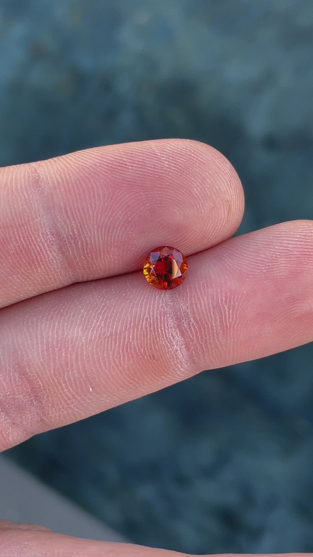 A video of a dazzling 1.25-carat Hessonite Garnet in round brilliant cut, revealing its orange and brown hues in various lighting.