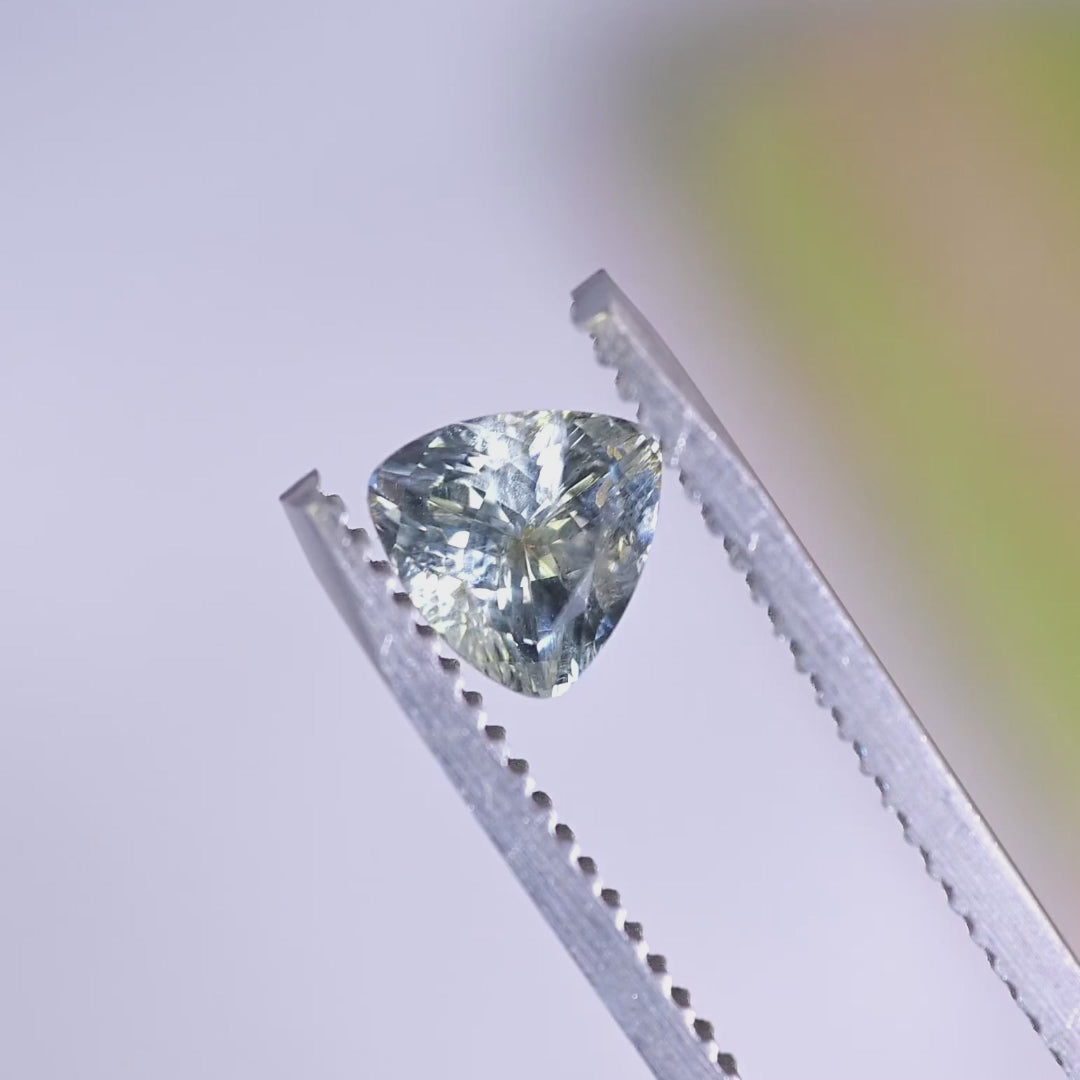 Close-up video of 1.01 carat untreated Montana sapphire trillion cut displaying green, yellow and gray tones in motion