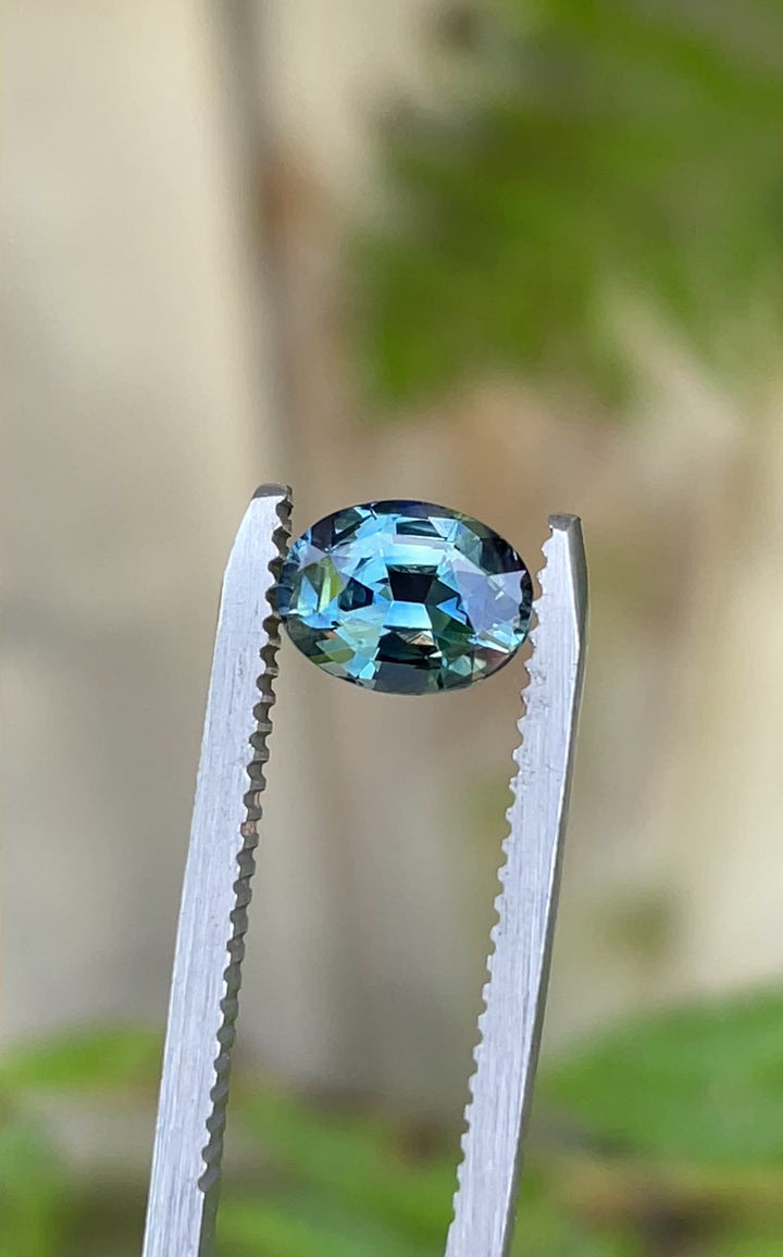 360-degree video showcasing the brilliance and color play of a 1.30-carat untreated sapphire in teal-blue-green, filmed outdoors for clarity.