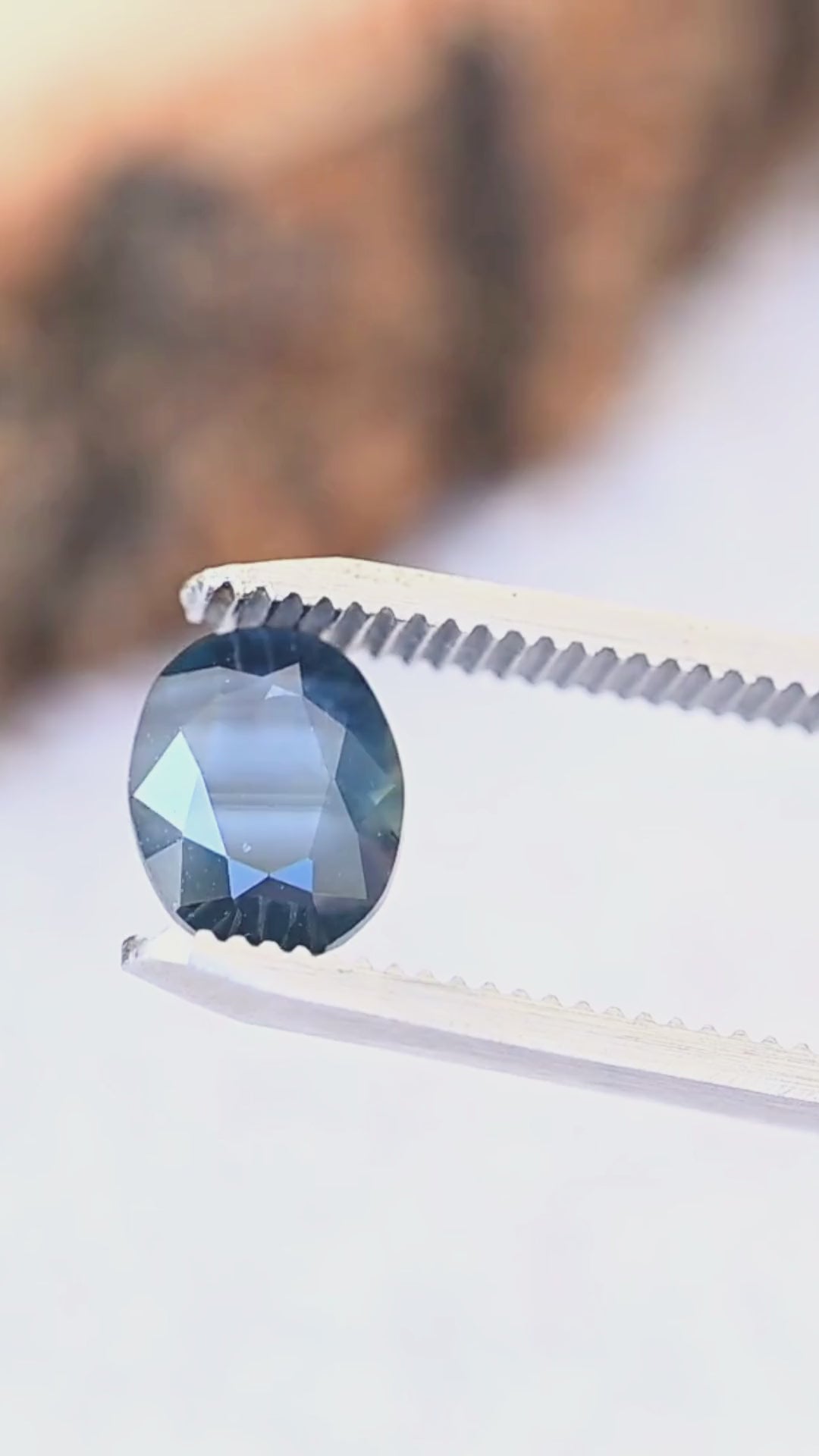 A close-up look at the natural parallel blue bands, deep navy tones and faceted oval shape of this untreated 2.98ct sapphire from Gombe, Nigeria.