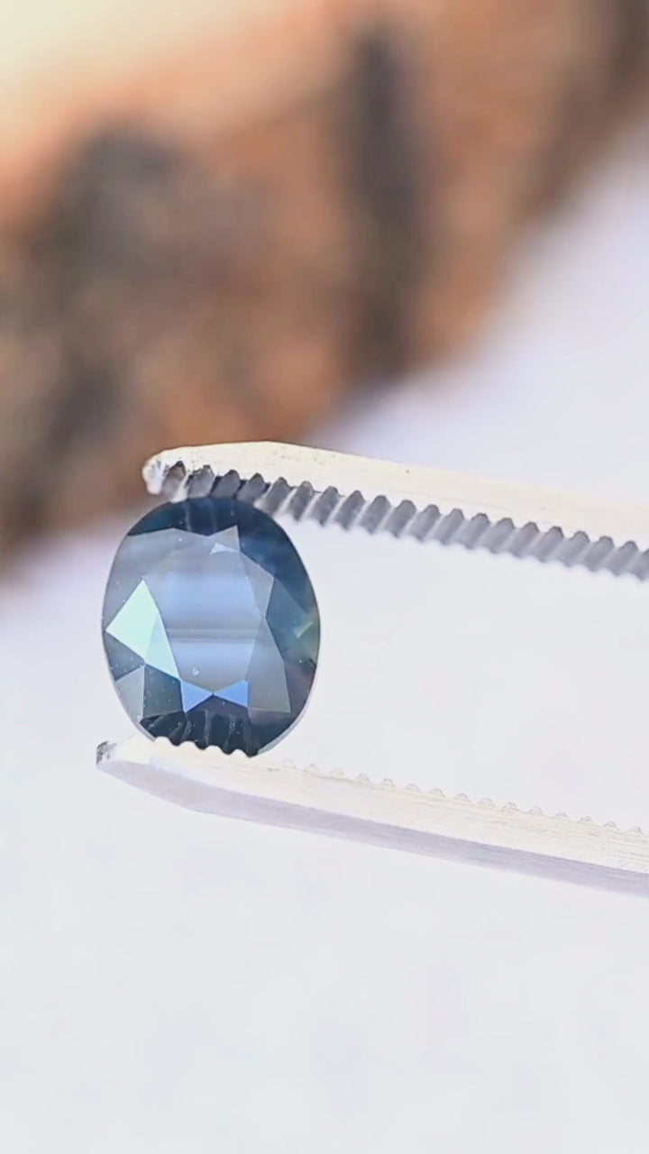 A close-up look at the natural parallel blue bands, deep navy tones and faceted oval shape of this untreated 2.98ct sapphire from Gombe, Nigeria.