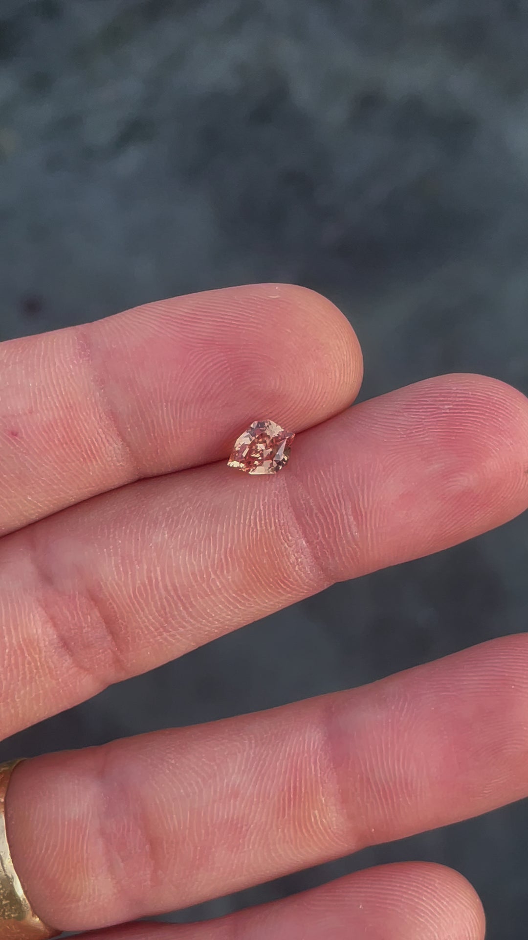 This video features a close-up of a 1.59-carat sapphire with a custom geometric shield cut, highlighting its orange and brown tones. As the gemstone is tilted and turned, the light captures the depth and warmth of its color.