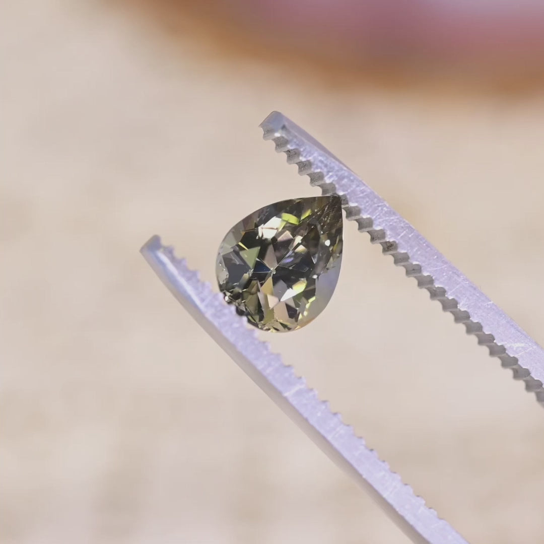1.32 carat pear brilliant Tanzanite rotating under light showing green brown purple color play brilliance and fire from Merelani Hills Tanzania