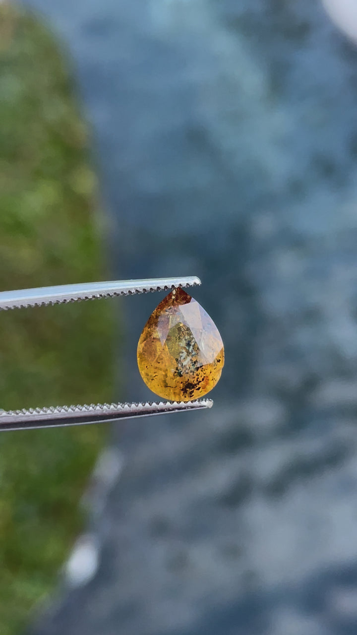 A video demonstrating the brilliance and unique inclusions of a 3.03-carat yellow-orange sapphire, highlighting its pear-modified cut." Title: "Close-up Video of 3.03-carat Sapphire