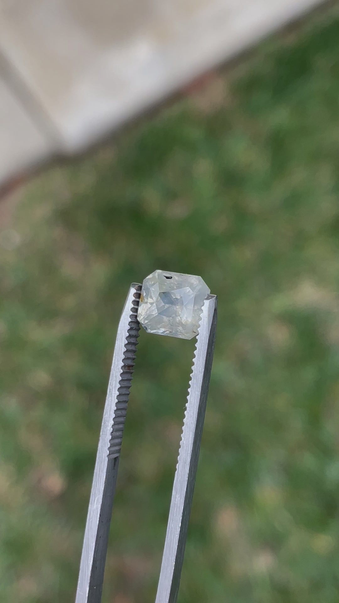 Close-up rotating view of a custom radiant-cut sapphire in pale yellow, gray, and blue tones, weighing 3.60 carats.