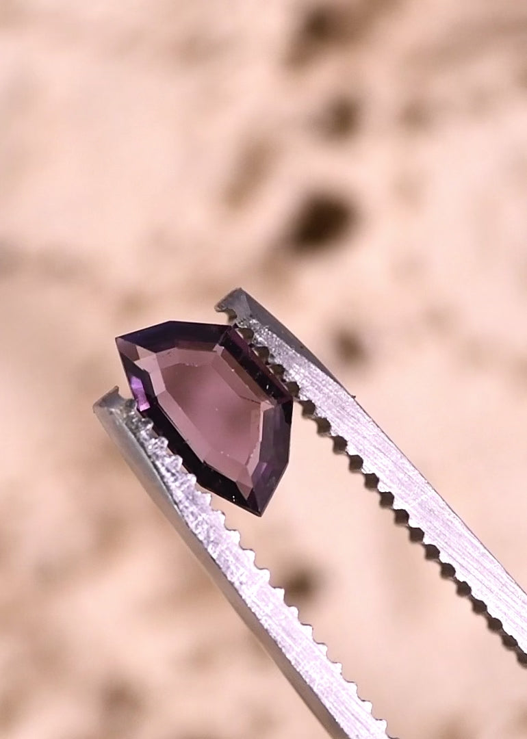 Video of 0.70ct purple pink spinel rotating in tweezers, geometric step cut portrait from Sri Lanka showing light return and shifting violet pink hues