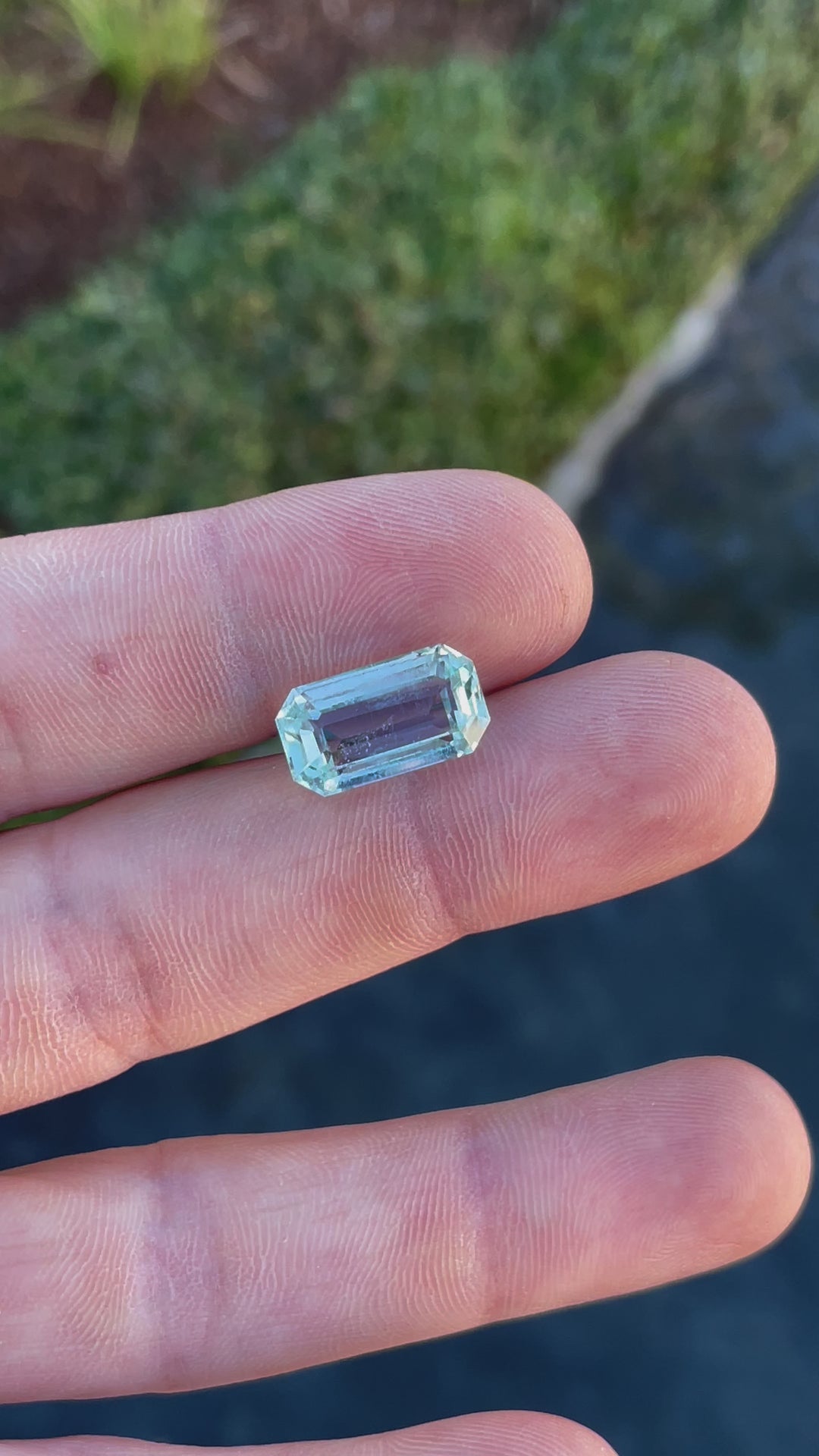 Rotating view of an 8.80-carat aquamarine gemstone held on hand, highlighting its emerald cut and mint blue-green tones.