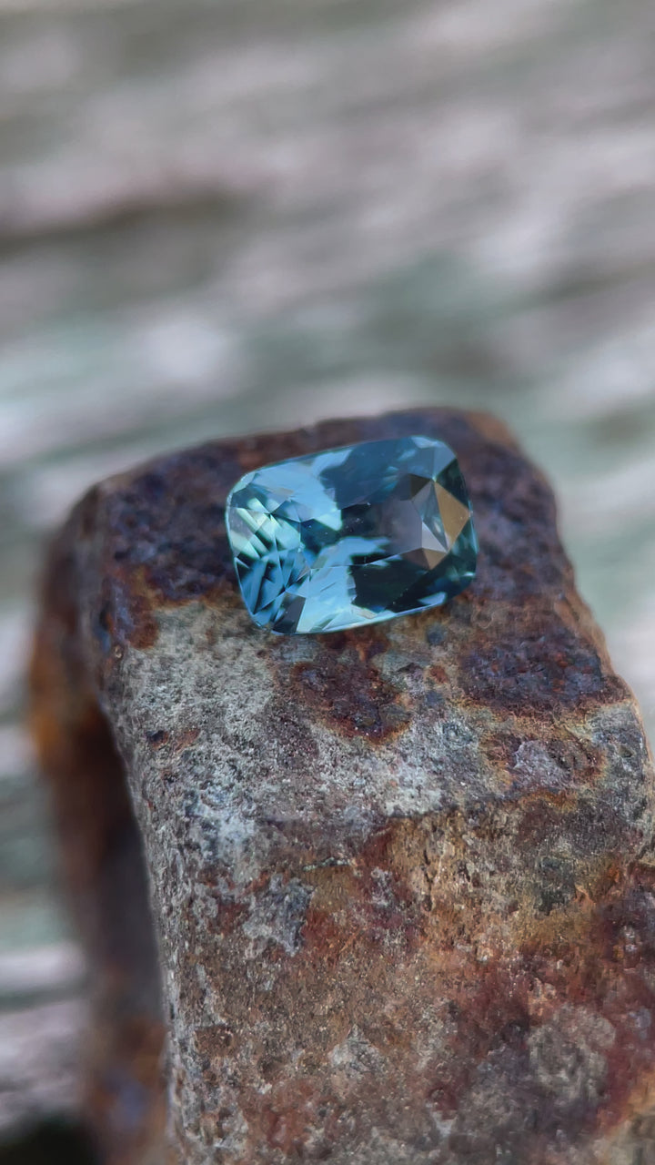 A detailed video of a denim blue and green sapphire in tweezers, displaying its brilliance and Sri Lankan craftsmanship.