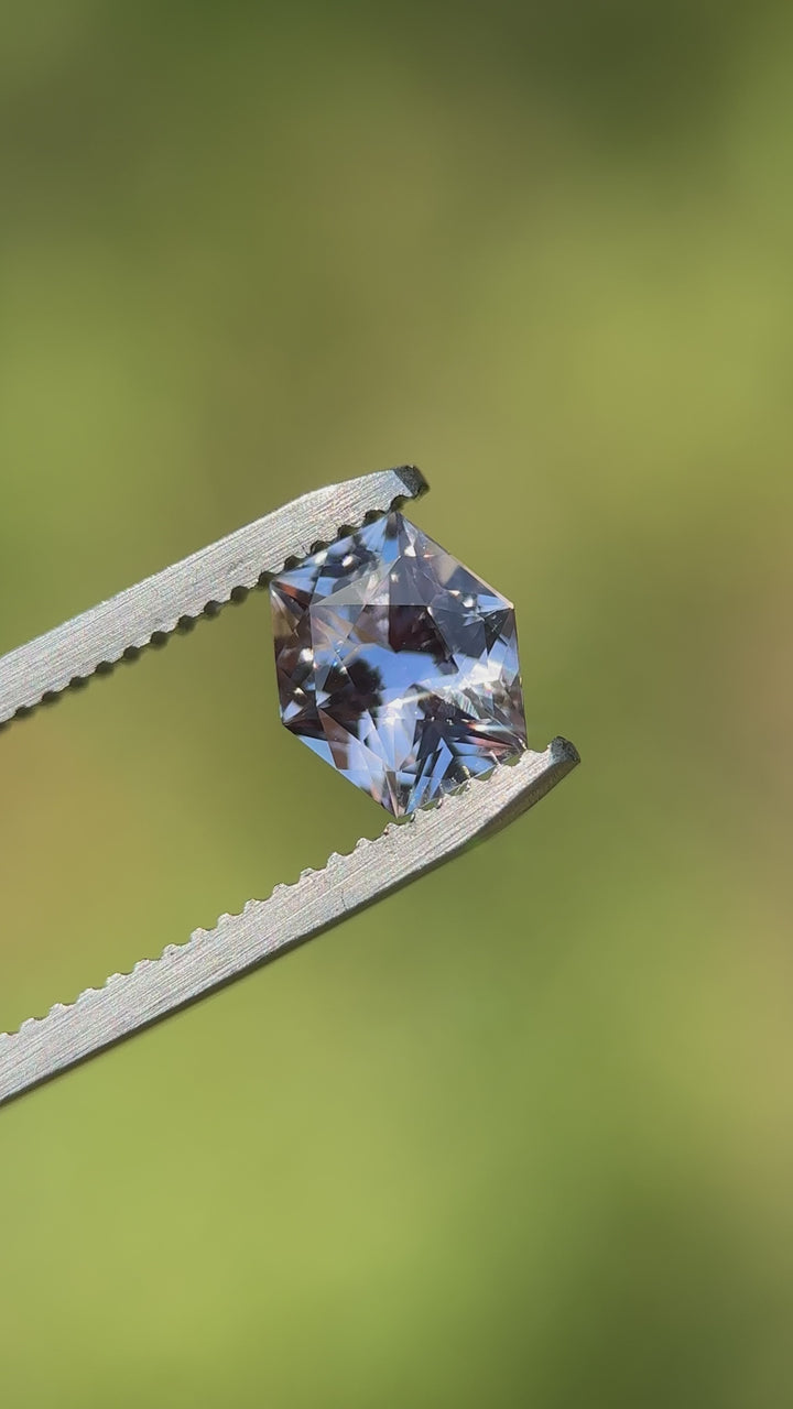 Color shift sapphire filmed in natural lighting showing vivid purple to subtle grey transition in hexagonal cut