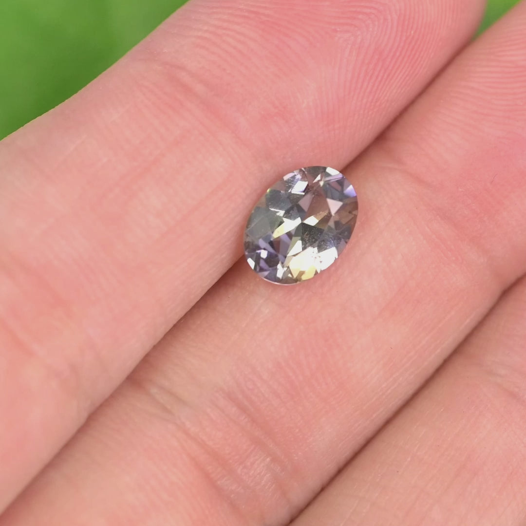 1.69 carat blue purple yellow Tanzanite oval rotating under natural light, mix modified brilliant cut from Merelani Hills Tanzania showing trichroic color shift and sparkle for custom jewelry