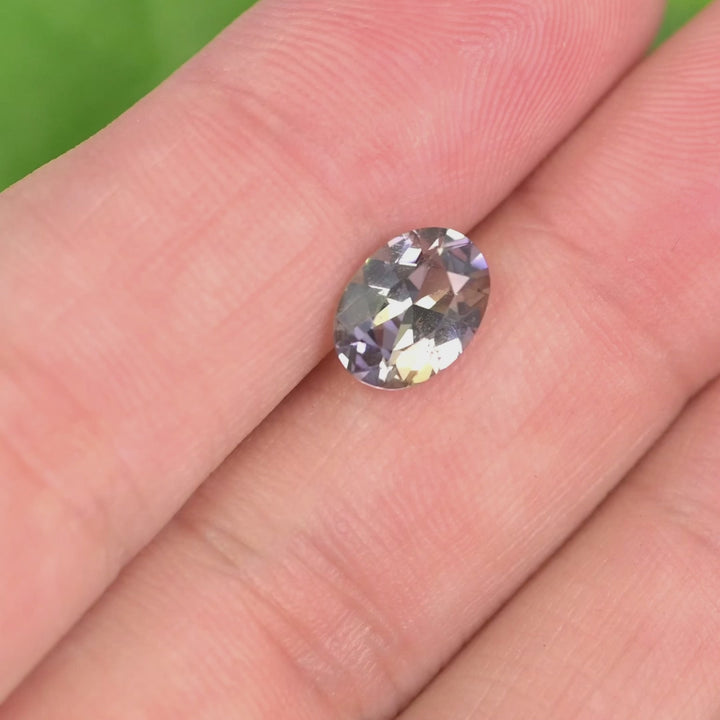 1.69 carat blue purple yellow Tanzanite oval rotating under natural light, mix modified brilliant cut from Merelani Hills Tanzania showing trichroic color shift and sparkle for custom jewelry