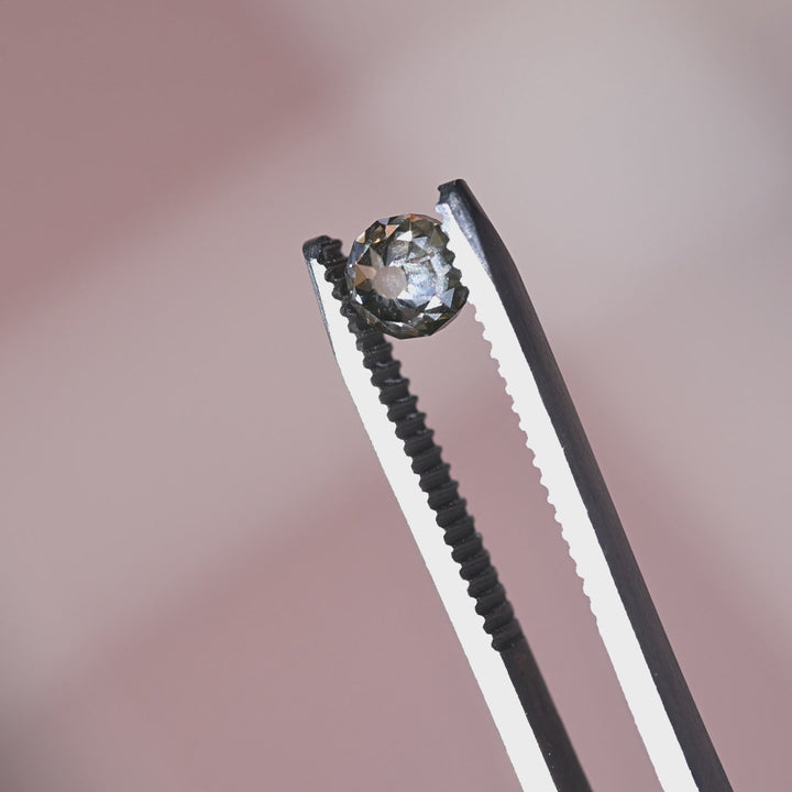 Loose rosy champagne fancy brown Mughal cut diamond from South Africa turning in tweezers, showcasing its antique faceting and strong fluorescence character.