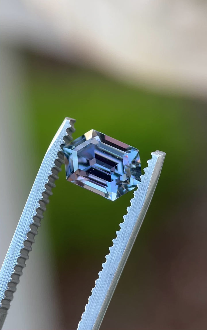Rotating video of a 1.60ct Tanzanite gemstone with step cut hexagon facets in blue and violet hues, shot outdoors