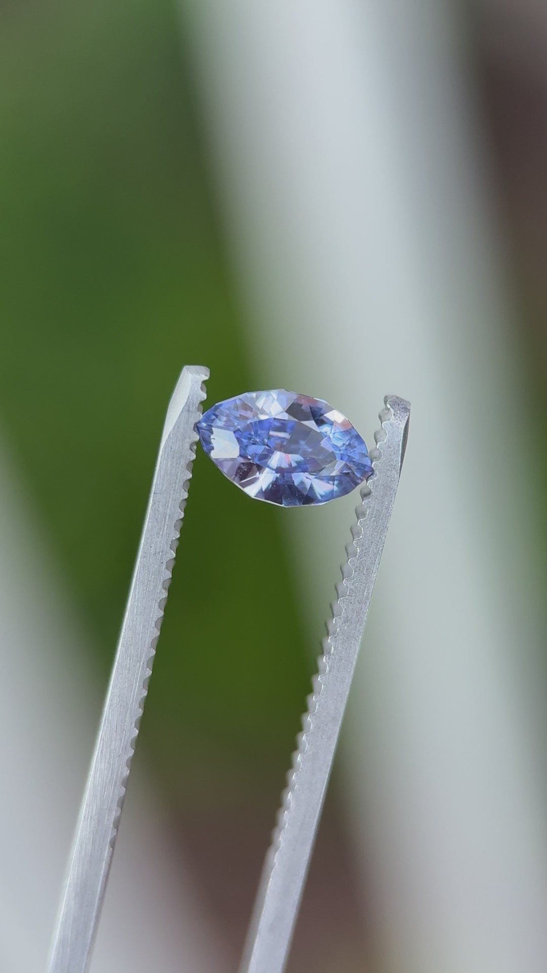 Close-up video of 1.03CT indigo and purple sapphire rotating in gemstone tweezers, highlighting brilliance, luster, and precise faceting of the marquise mixed cut, unheated sapphire from Sakaraha, Madagascar.