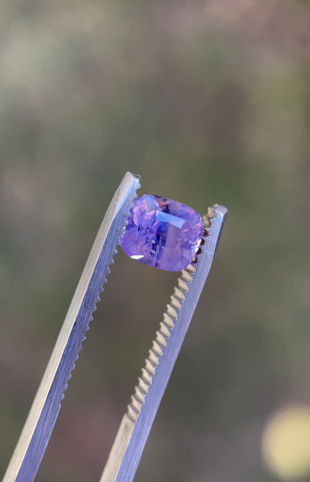 A 360-degree rotating view of a 2.00-carat opalescent pink and violet sapphire, revealing its mesmerizing cushion mix cut and brilliance under natural light. Ethically sourced from Sri Lanka.