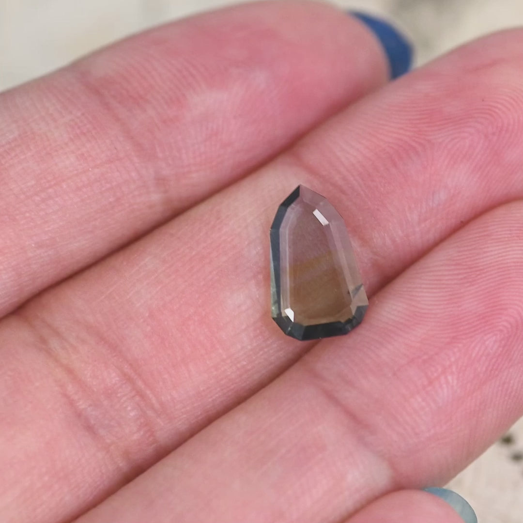1.42 carat yellow teal green blue Tanzanite shield portrait cut rotating under natural light, rare flat faceted gemstone from Merelani Hills Tanzania showing color shift and transparency for custom jewelry design