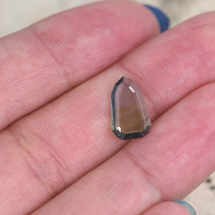 1.42 carat yellow teal green blue Tanzanite shield portrait cut rotating under natural light, rare flat faceted gemstone from Merelani Hills Tanzania showing color shift and transparency for custom jewelry design
