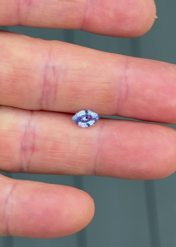 Video of 1.03 carat indigo-purple sapphire resting on fingertip under natural light, showing shifting hues and reflections from the precision marquise mixed cut, untreated sapphire from Sakaraha, Madagascar.