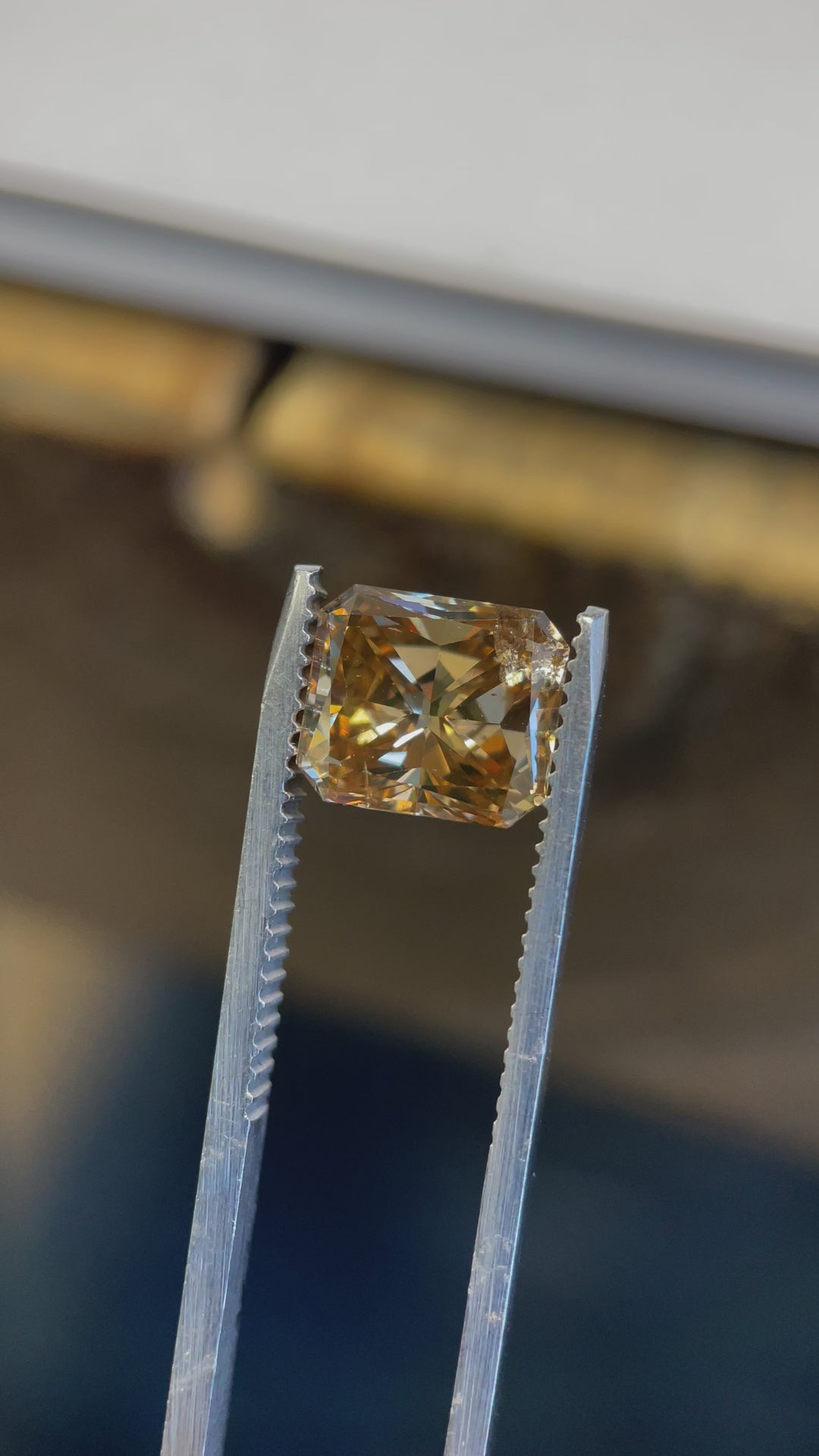 Close-up video of a 3.68CT fancy brown-yellow diamond, showcasing its radiant cut facets and natural inclusions under different lighting angles.