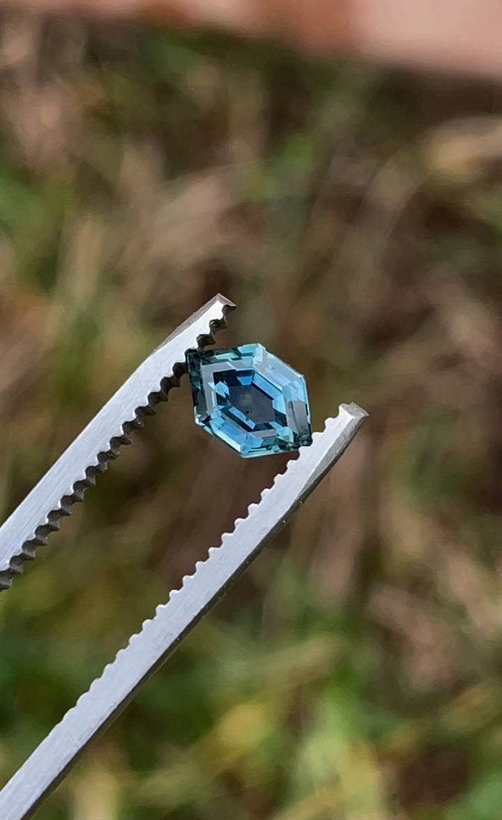 A video showing the 0.82-carat Montana sapphire in a hexagonal cut, with teal and blue hues shimmering as the gemstone rotates under light.