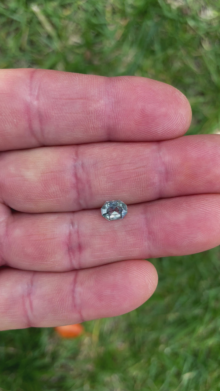 A close-up video of the 0.86-carat custom octagonal radiant cut sapphire. The yellow and seafoam hues shimmer against a soft backdrop, revealing its clean facets and natural brilliance.