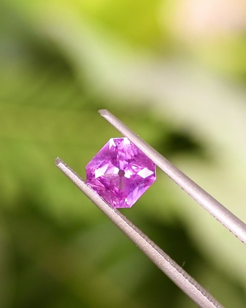 Video of 1.03CT pink and purple sapphire rotating in gemstone tweezers, showing brilliance, clean lines, and vivid hues of the square scissor cut, untreated sapphire from Sakaraha, Madagascar.