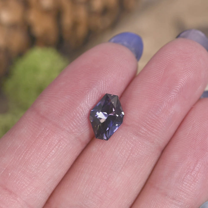 2.19 carat peach lavender blue purple Tanzanite geometric asymmetrical octagon rotating on hand under natural light, precision faceted Merelani Hills gemstone showing vivid color shift and angular brilliance for custom jewelry design