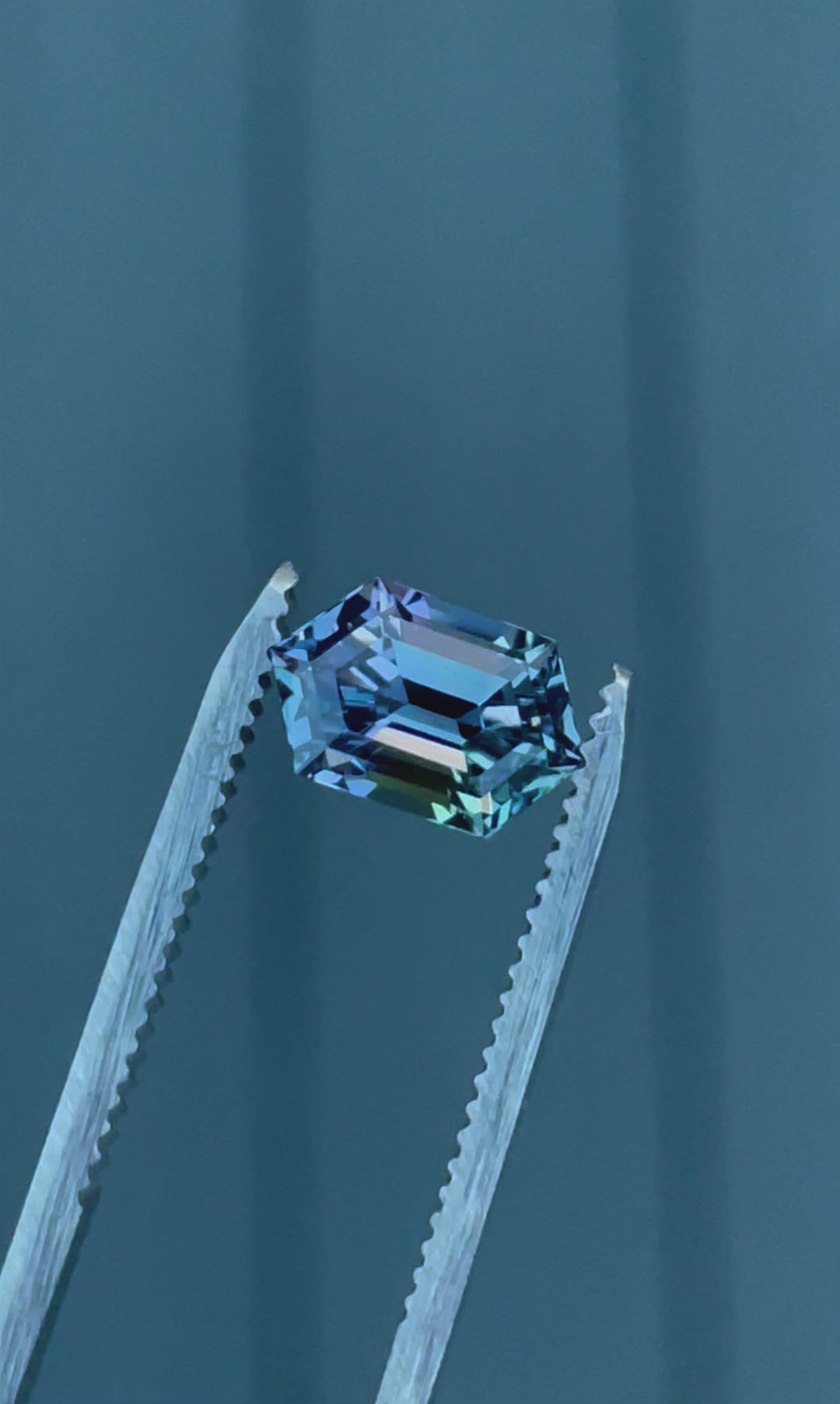 A 360-degree video of a 2.08-carat Tanzanite gemstone, exhibiting a mesmerizing step-cut hexagonal shape with mermaid hues of teal, violet, and blue, reflecting light from every angle.