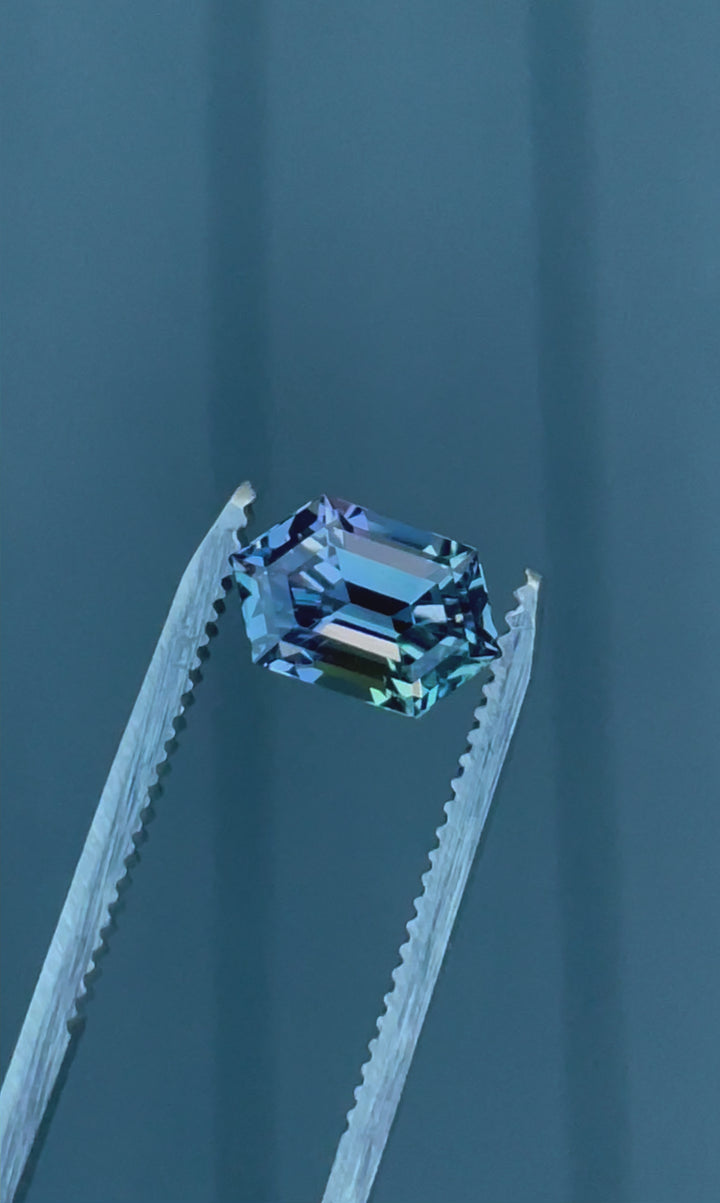 A 360-degree video of a 2.08-carat Tanzanite gemstone, exhibiting a mesmerizing step-cut hexagonal shape with mermaid hues of teal, violet, and blue, reflecting light from every angle.