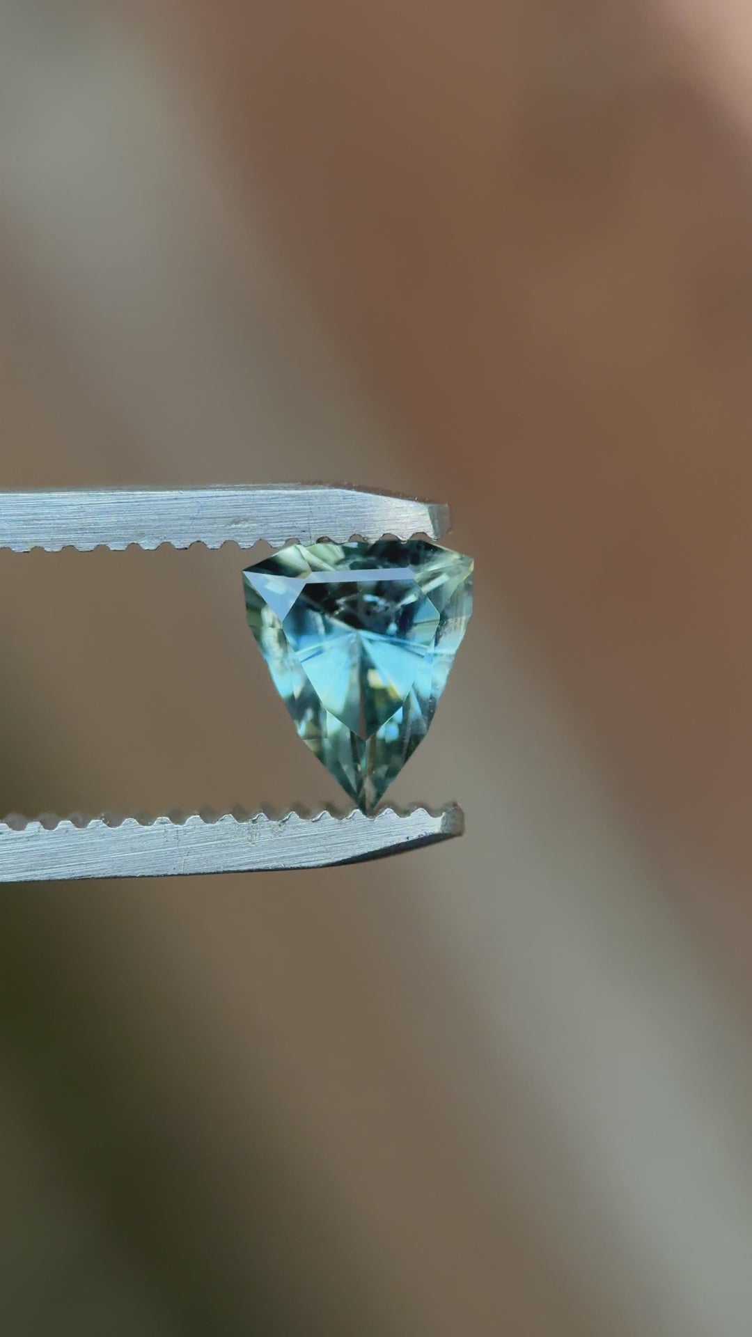 Rotating close-up of 1.08ct custom shield cut sapphire showing teal and sky blue sparkle, natural and untreated from Malawi.