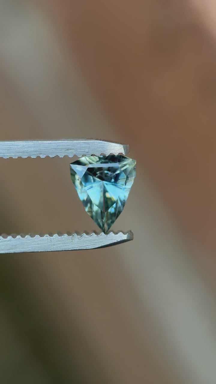 Rotating close-up of 1.08ct custom shield cut sapphire showing teal and sky blue sparkle, natural and untreated from Malawi.