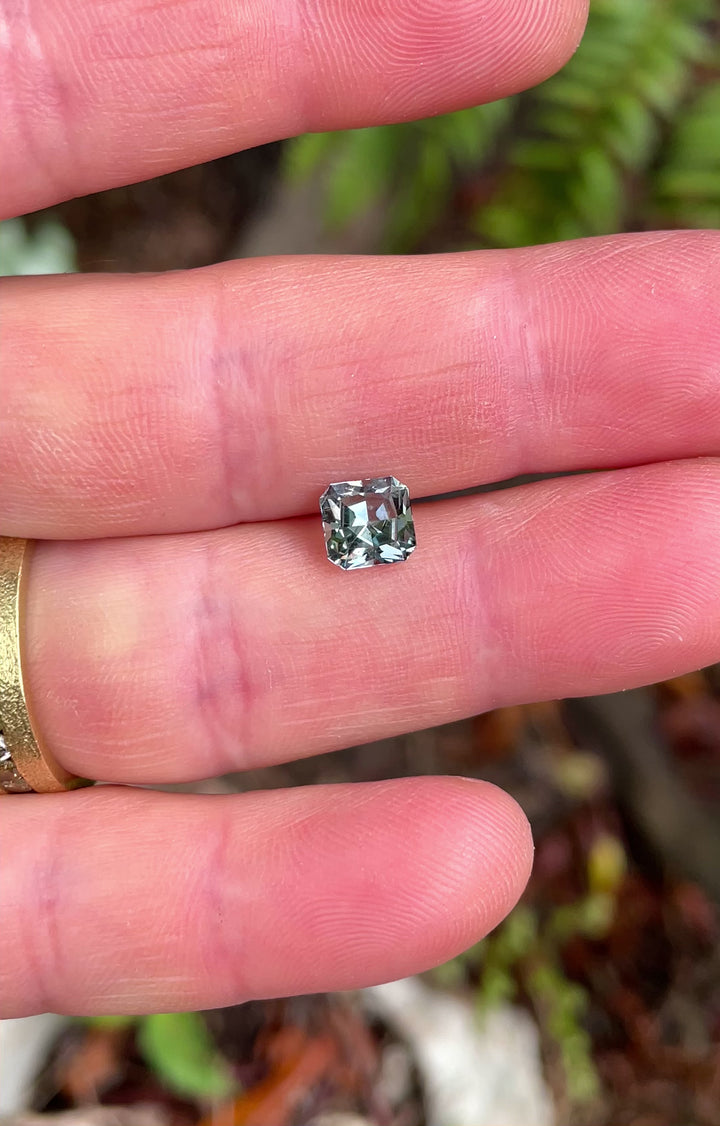 Handheld video of a 1.58ct sapphire from Montana, capturing the sparkle and color shifts of its steely sage grey green custom cut under daylight.