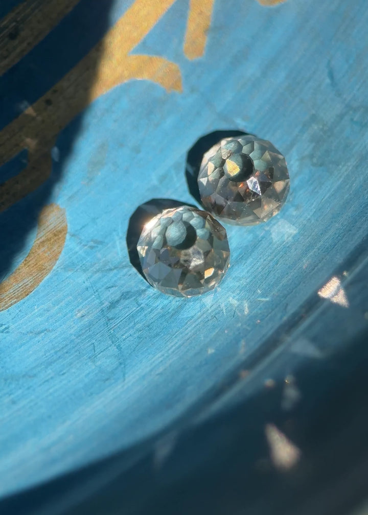 Video of a matching pair of fancy brown Mughal cut diamonds rotating under mixed lighting, revealing antique hand-cut facets, VVS1 clarity, subtle blue and yellow fluorescence, and natural untreated South African diamonds.