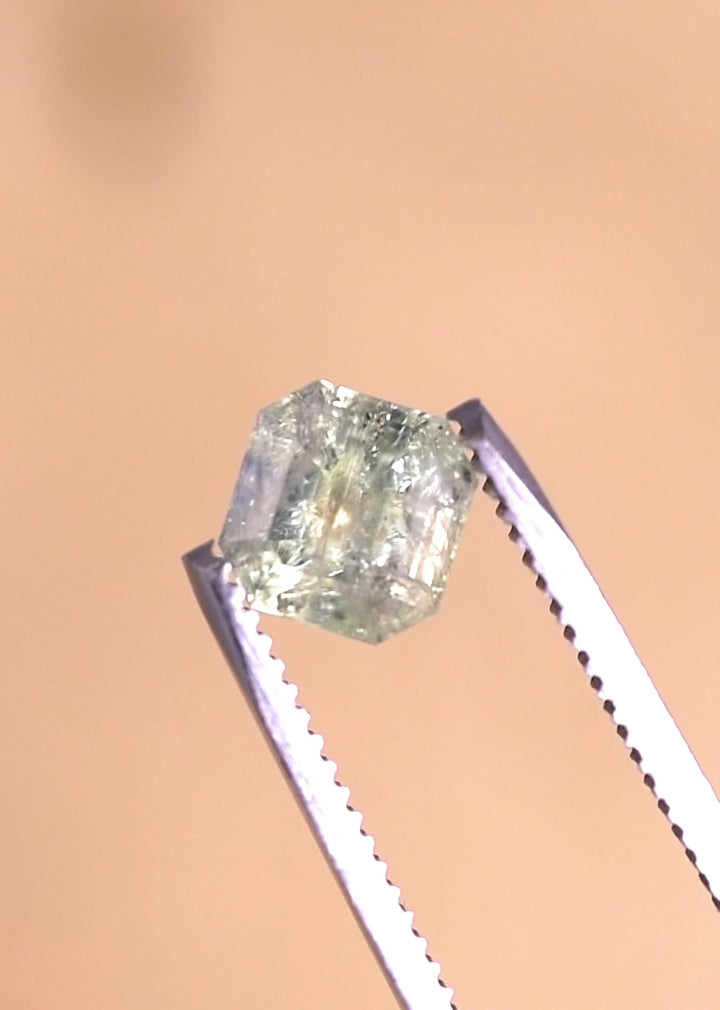 Rotating video of a 2.25 carat untreated Montana sapphire in a seafoam and teal Asscher cut, held in gem tweezers to reveal step-cut reflections, natural inclusions, and color zoning from multiple angles.