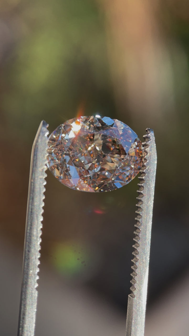 A 5.25 Carat Light Champagne Diamond with Strong Rosiness and Blue Fluorescence being rotated to display its brilliance, SI2 clarity, and exceptional cut.