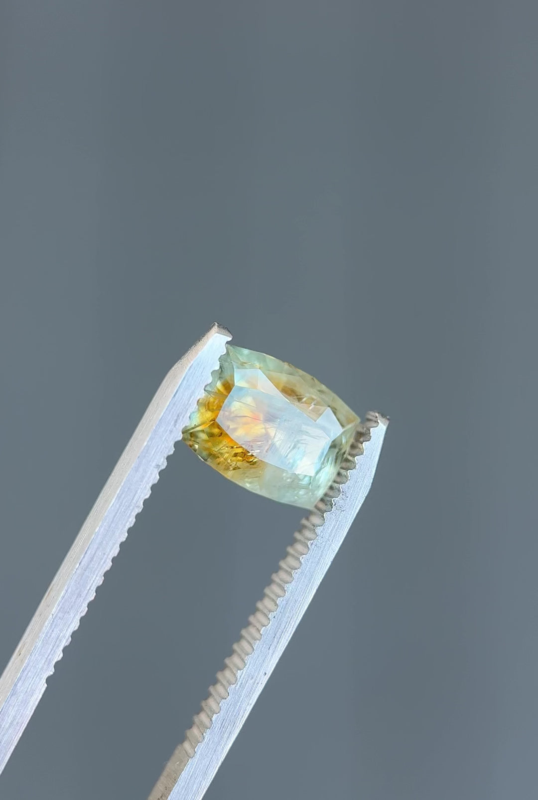 Video showing a 360-degree spin of a 2.99ct custom elongated cushion Montana sapphire with striking teal and orange parti coloration in natural light.