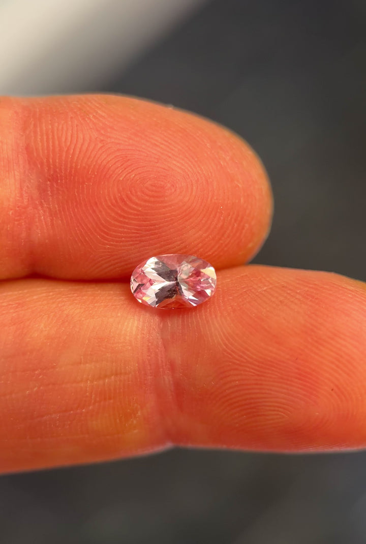 Hand video of 1.50ct natural salmon pink sapphire in oval modified brilliant cut showing light reflection and clarity