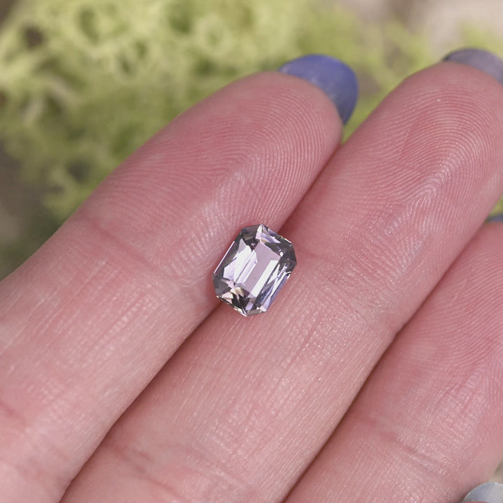 1.56 carat purple champagne teal Tanzanite modified radiant rotating on hand under natural light, precision faceted Merelani Hills gemstone showing dynamic color shift and brilliant rectangular sparkle for custom jewelry design